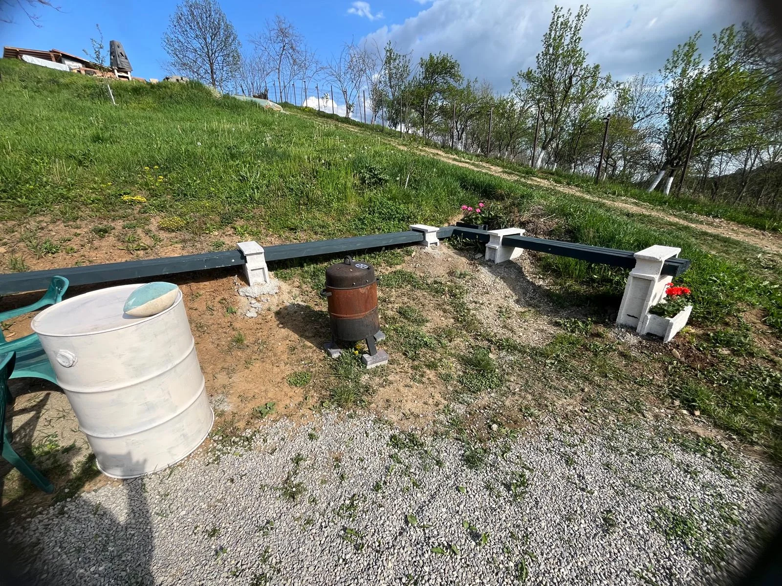 Gratarul metalic cilindric langa dusuri — Tent pitch – main area - Camping Be You Văleni